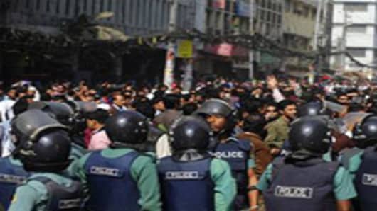 Bangladeshi police look on as a crowd of investors shout slogans during a protest in front of The Dhaka Stock Exchange in Dhaka.