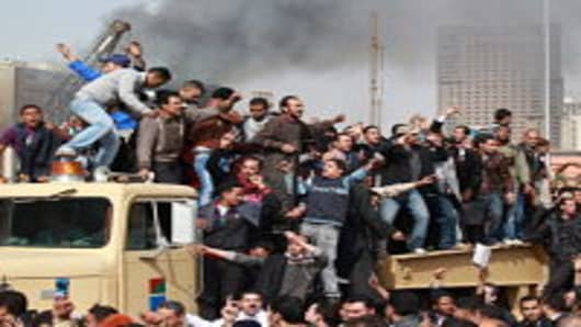 Protestors chant as they ride on an army tank transporter in Tahrir Square on January 29, 2011 in Cairo, Egypt. Tens of thousands of demonstrators have taken to the streets across Egypt in Cairo, Suez, and Alexandria to call for the resignation of President Hosni Mubarak. Riot police and the Army have been sent into the streets to quell the protests, which so far have claimed 32 lives and left more than a thousand injured.