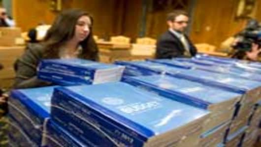 Dylan Morris of the Senate Budget Committee stacks copies of President Obama's budget for 2012 in the Committee's hearing room in Dirksen Building.