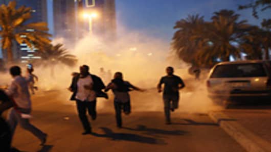 Protesters run from a cloud of teargas during a clash with Bahraini security forces near the Pearl roundabout in Manama, Bahrain. Protesters said that the army fired on them with live rounds, followed by teargas which drove the demonstrators back. There are unconfirmed reports that there are four dead in the clashes.