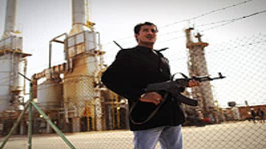 A rebel militiaman stands guard at a Libyan oil refinery in rebel-held territory on February 27, 2011 in Al Brega, Libya. The opposition leadership has stressed that oil faciities in areas under its control are safe, despite the conflict roiling the country.