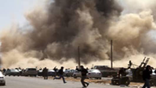 Libyan rebel fighters take cover as a bomb dropped by an airforce fighter jet explodes near a checkpoint on the outskirts of the oil town of Ras Lanuf on March 7, 2011. AFP PHOTO/MARCO LONGARI (Photo credit should read MARCO LONGARI/AFP/Getty Images)