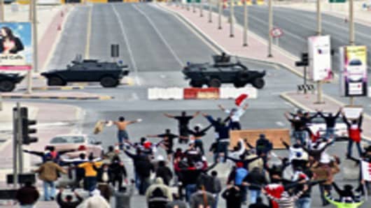 Anti-government protestors open their arms in front of military vehicles near Pearl Square in Bahraini capital Manama, on March 16, 2011, after Bahraini police killed at least two protesters and wounded dozens more as they assaulted a peaceful protest camp in the capital's Pearl Square, an opposition party official said. AFP PHOTO/STR (Photo credit should read -/AFP/Getty Images)