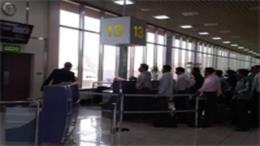 Passengers line up for flights out of Bahrain at the country's airport March 17.