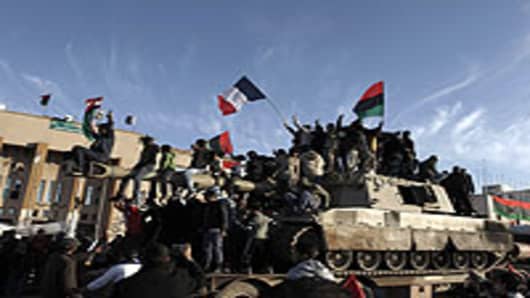 Libyans wave the French flag as they parade on a 155mm Howitzer belonging to Muammar Gaddafi forces in the eastern rebel-held city of Benghazi on March 21, 2011.