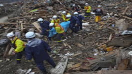 Rescue workers carry a body from the rubble in Rikuzentakata, Japan.