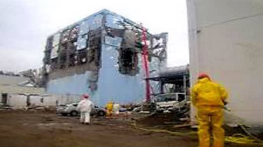 TEPCO workers in protective suits conduct a cooling operation by spraying water at the damaged No. 4 unitP at the Fukushima Daiichi nuclear complex.