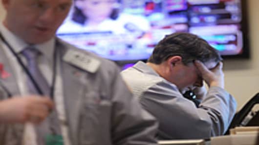 A trader holds his head in his hand on the floor of the New York Stock Exchange in New York City