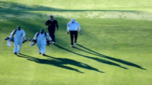 Adam Scott of Australia and Nick Watney (R) walk with their caddies on the first hole during the first round of the 2011 Masters Tournament at Augusta National Golf Club on April 7, 2011 in Augusta, Georgia.