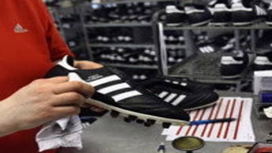 An employee examines football boots at the final check of the factory of German sporting-goods maker Adidas AG in Scheinfeld, Germany.