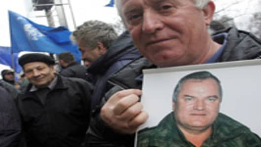BELGRADE, SERBIA - FEBRUARY 24: A Serbian Radical party supporter holds a photo of war crimes suspect Ratko Mladic at a rally in Belgrade February 24, 2006. A Serbian ultranationalist party on Thursday urged fugitive Bosnian Serb general Ratko Mladic not to surrender to the UN warcrimes court, despite mounting pressure on Belgrade to hand over one of the most wanted suspects of the Balkan wars in 1990s. (Photo by Milos Bicanski/Getty Images)