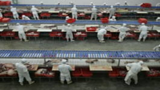 Workers process pork at a slaughtering factory September 26, 2007 in Beijing, China.