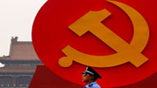 A policeman patrols under a giant communist emblem on the Tiananmen Square on June 28, 2011 in Beijing, China.