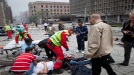 njured people are treated by medics at the scene of an explosion near the government buildings in Norway's capital Oslo.