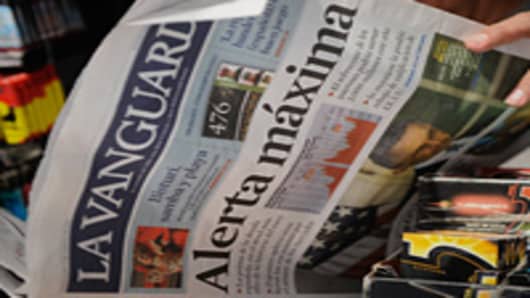 A customer reads an edition of La Vanguardia newspaper with the front page headline' Maximum Alert' about the Spanish and Italian bond crisis.