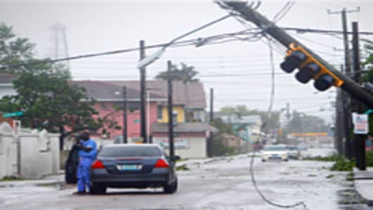 Man takes pictures of utility poles downed from winds from Hurricane Irene, New Providence Island, Bahamas.