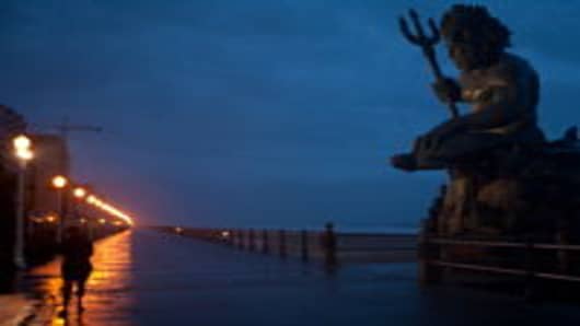 Susan Petrella, lower left, stands near the King Neptune statue as the first wind and rain of Hurricane Irene blow in on August 27, 2011 in Virginia Beach, VA.