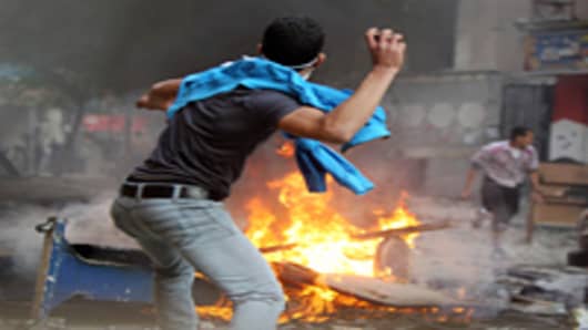 An Egyptian protester throws a stone on the third day of clashes with security forces at Tahrir Square in Cairo on November 21, 2011.