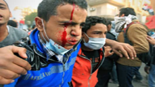 An injured Egyptian protester is helped away during clashes with security forces on the third day at Tahrir Square in Cairo on November 21, 2011.