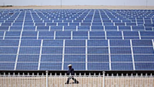 A Chinese worker walks near the solar modules of a newly installed 100MW photovoltaic on-grid power project in Dunhuang of China's northwest Gansu Province.