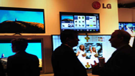 People mingle in front of a display of LG Electronics televisions.