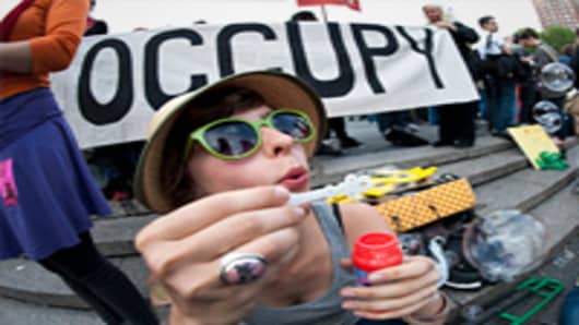 Katie, a college graduate, blows bubbles during an Occupy Wall Street rally against the high cost of college tuitions on April 25, 2012 in New York.