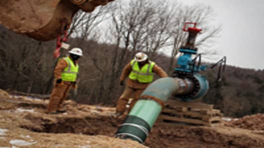 Men work on a natural gas valve at a hydraulic fracturing site.