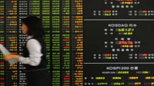 An employee of a securities company walks past a stock index board in Seoul, South Korea