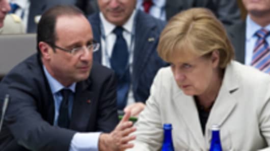 French President Francois Hollande (L) speaks with German Chancellor Angela Merkel (R)