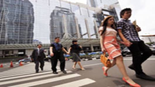 Pedestrians cross a street in Jakarta's modern business district.
