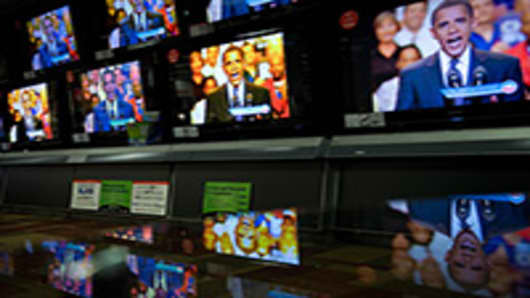President Barack Obama is reflected on a glass table as he appears on television screens at an electronics shop in 2008 during a segment of a 30-minute prime-time infomercial.