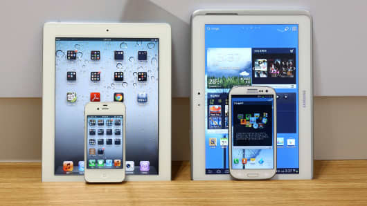An Apple iPad 2 and iPhone 4S smartphone, left, and a Samsung Electronics Galaxy Tab 10.1 tablet computer and Galaxy S III smartphone.