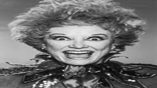 Headshot portrait of American comedian Phyllis Diller posing wide-eyed and openmouthed in an outfit with a sequined court jester's collar, circa 1984.