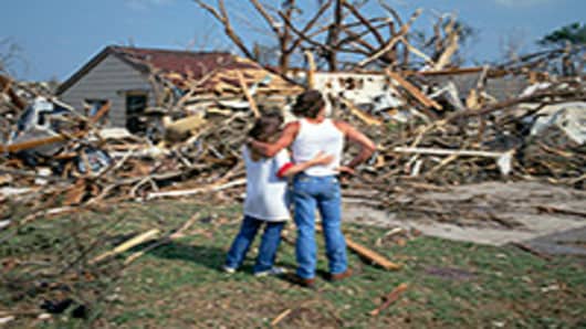 Couple looking at their home damaged by a tornado.