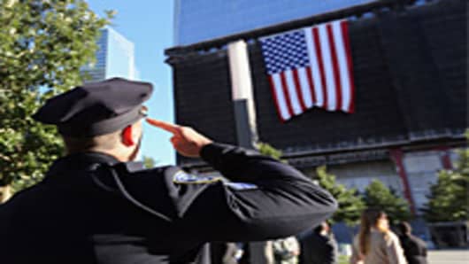 A New York City policeman salutes a flag hanging from One World Trade ceremonies for the eleventh anniversary of the terrorist attacks on lower Manhattan at the World Trade Center on September 11, 2012 in New York City.