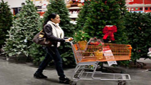 A shopper pushes a cart past a display of artificial Christmas trees at a Home Depot store.