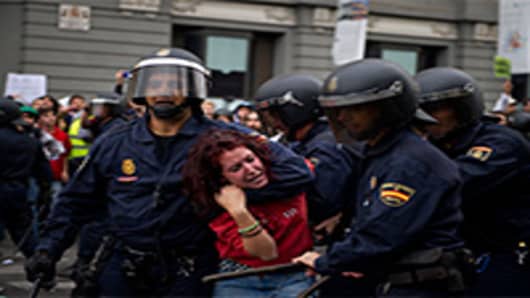 Riot policemen hold back a demonstrator during clashes around the Spanish parliament in a protest against spending cuts and the government of Mariano Rajoy. Madrid, Spain