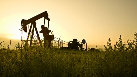 oil derrick in field at sunset
