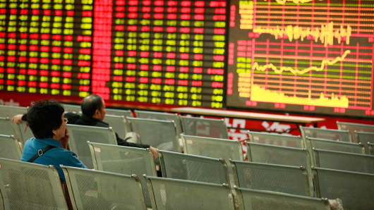 Investors watch the electronic board at a stock exchange hall in Huaibei, China.