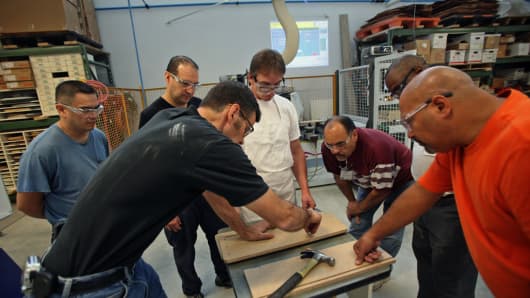 Instructor Doug Rappe, left, helps students participating in the woodworking manufacturing training program