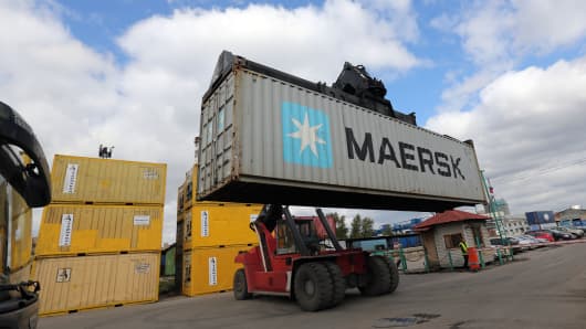 A worker drives a Kalmar reachstacker truck loaded with an AP Moeller-Maersk A/S shipping container.