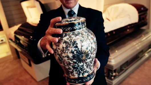 A funeral director of Greenwich Village Funeral Home, holds a cremation urn in the showroom of his funeral parlor in New York City.