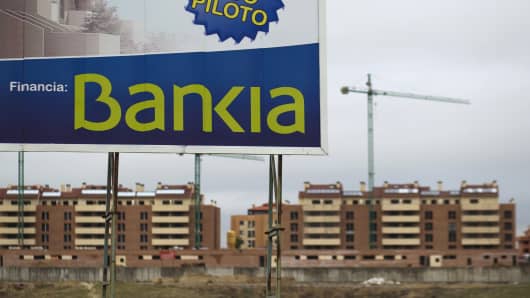 A sign reading "Visit our pilot housing, funded by Bankia" stands near new residential apartment blocks under construction in Navalcarnero, near Madrid, Spain.