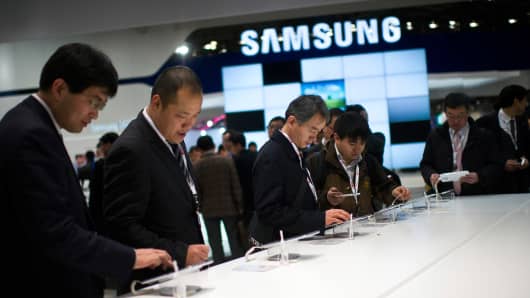 Visitors look at new Samsung devices during the first day of the Mobile World Congress 2013.