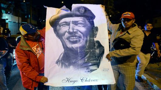 Supporters of Venezuelan President Hugo Chavez hold an allusive poster while gathering in front of the Military Hospital in Caracas on March 5, 2013, after knowing of their leader's death.