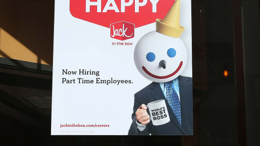 A sign advertising jobs is posted in the window of a Jack in the Box restaurant.