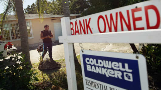 The yard around a foreclosed home is maintained by a bank-hired worker in Miami.