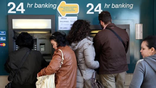 People withdraw money from an ATM in the Cypriot capital Nicosia. The Cyprus government postponed a planned emergency session of parliament on Sunday to debate a controversial EU bailout.