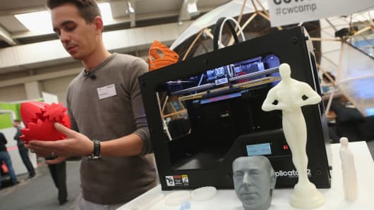 A host explains various objects created from molten plastic and a MakerBot 3-D printer at the 2013 CeBIT technology trade fair.