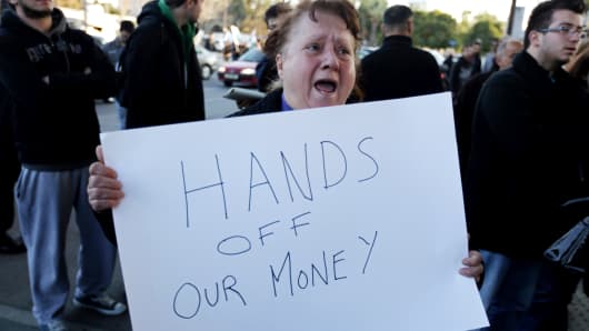 A Cypriot woman shouts slogans as she holds a placard during a protest against an EU bailout deal outside the parliament in Nicosia on March 19, 2013.